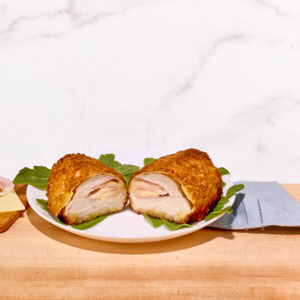 A ham and cheese stuffed chicken breast sliced in half on a plate.