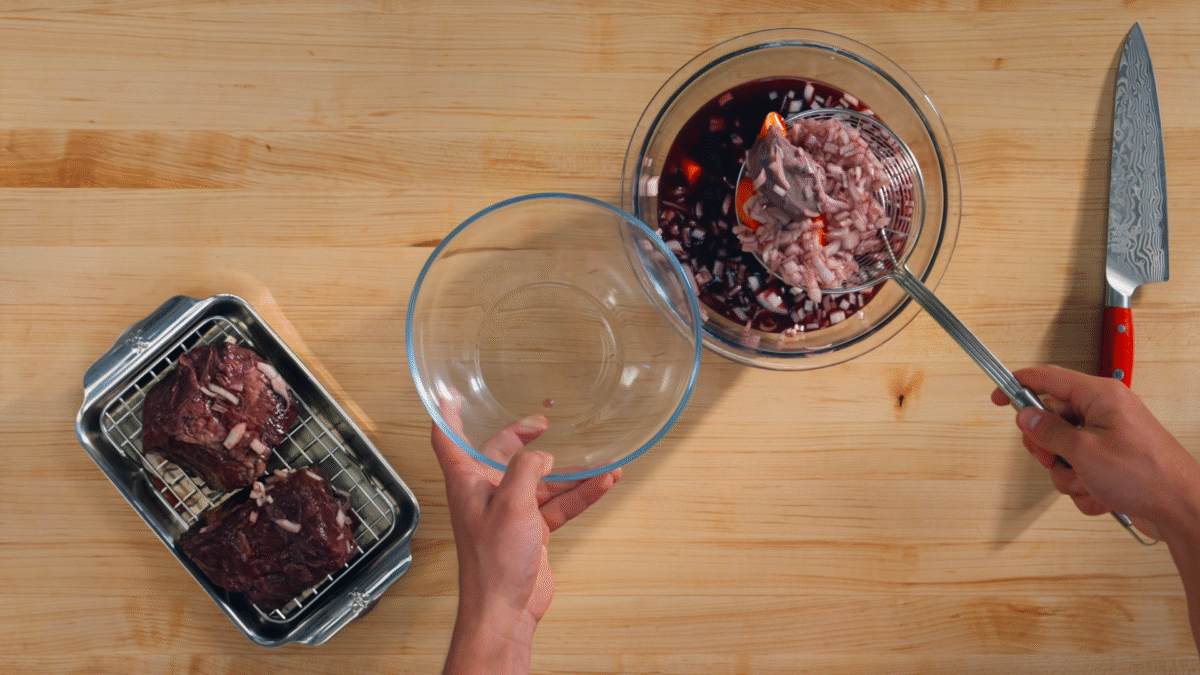 Nick DiGiovanni straining beef and vegetables from a bowl of red wine.