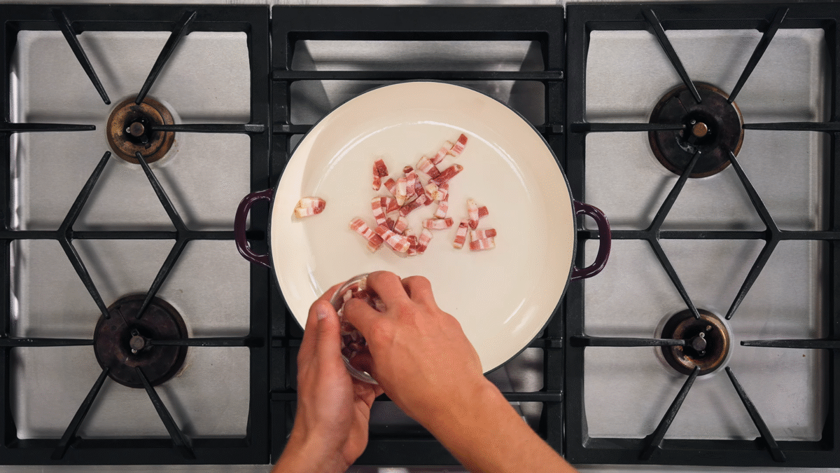 Nick DiGiovanni adding bacon pieces to a Dutch oven.