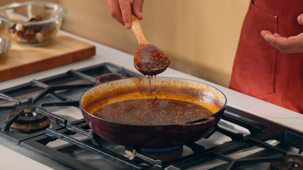 Nick DiGiovanni lifting beef bourguignon sauce from a pot with a wooden spoon.