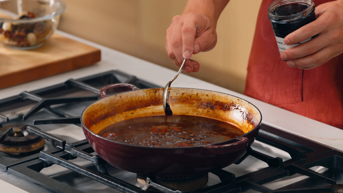 Nick DiGiovanni adding red currant jelly to a pot of beef bourguignon sauce.