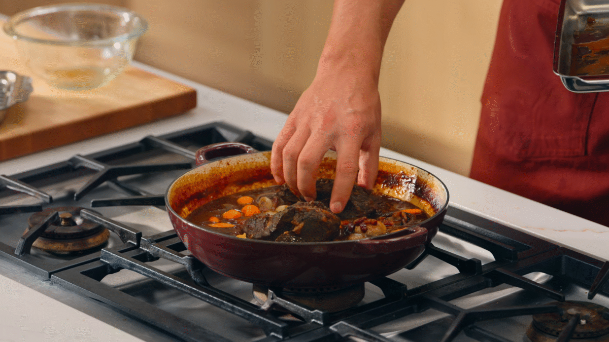 Nick DiGiovanni adding cooked chuck roast to a pan of red wine sauce and vegetables.