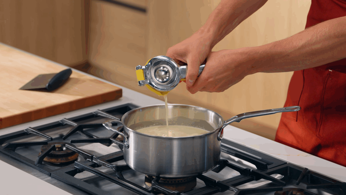 Nick DiGiovanni squeezing lemon juice into a pot of cream. 