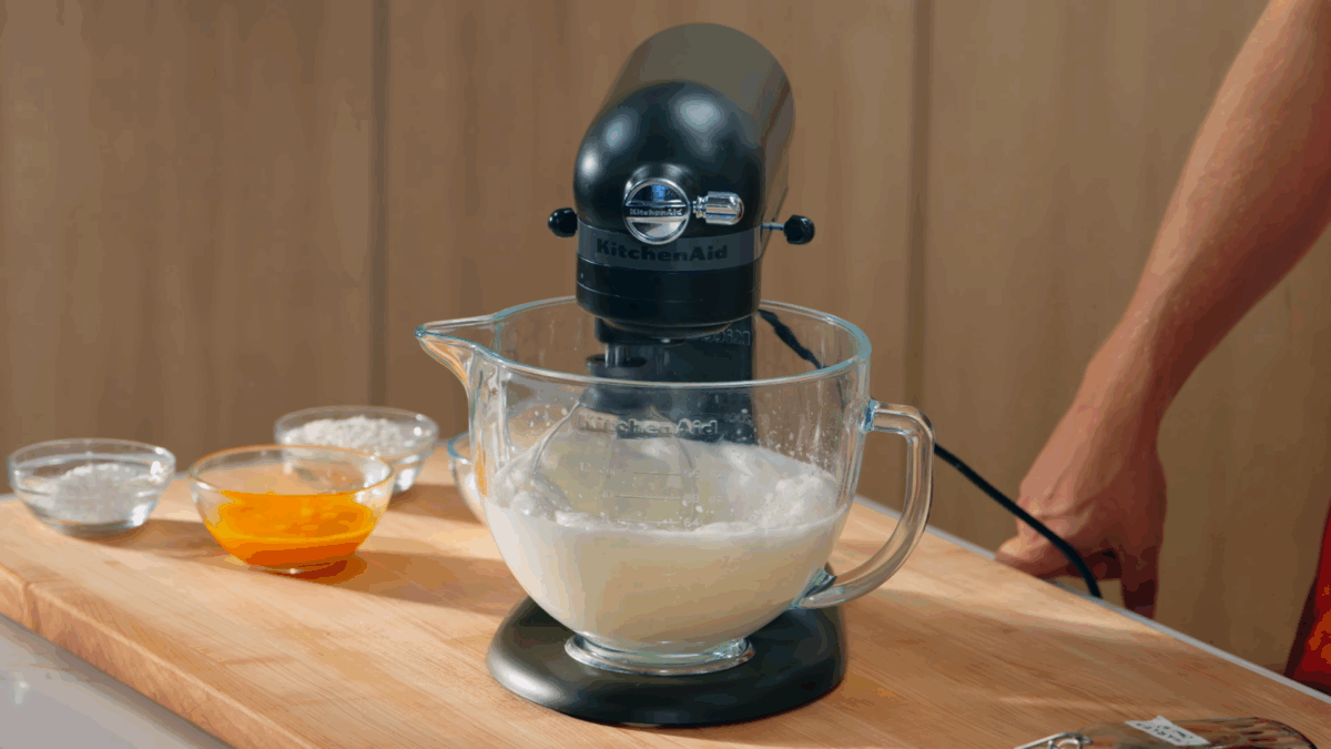 Egg whites being whipped in the bowl of a stand mixer. 