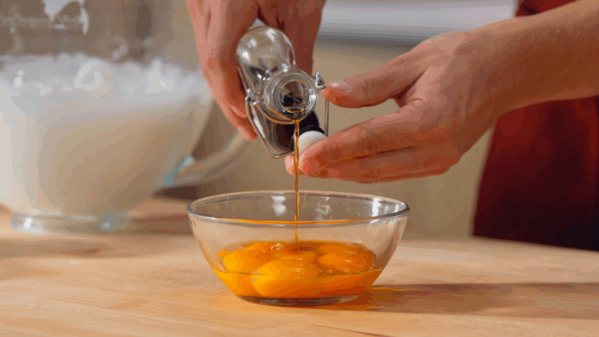 Nick DiGiovanni pouring vanilla extract into a bowl of egg yolks. 