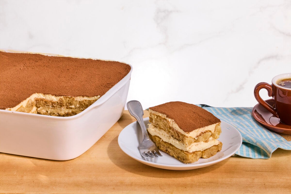 A dish of tiramisu with one serving missing and served on a plate.