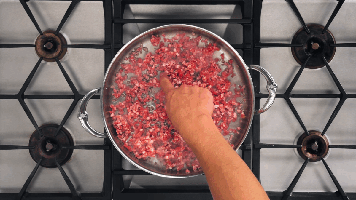 Nick DiGiovanni browning ground lamb in a sauté pan.