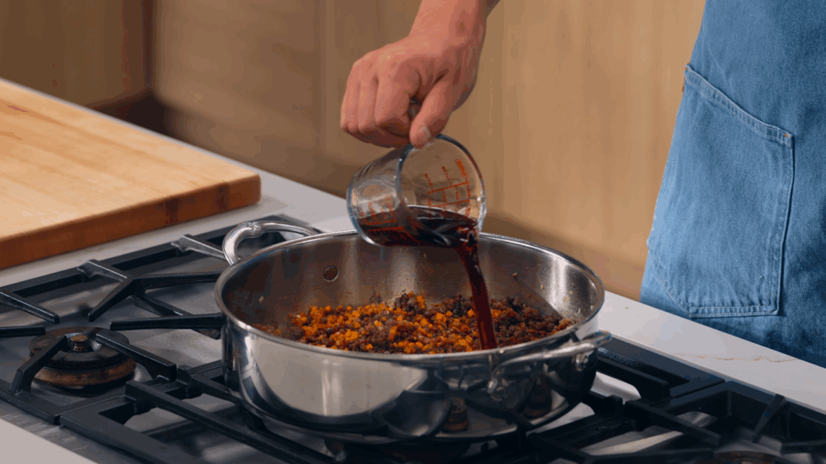 Nick DiGiovanni pouring broth into a pot of shepherd's pie filling.