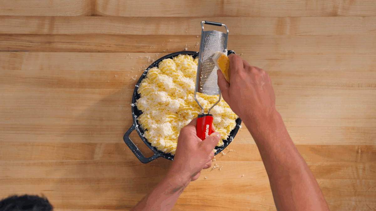 Nick DiGiovanni grating Parmesan over an unbaked shepherd's pie.